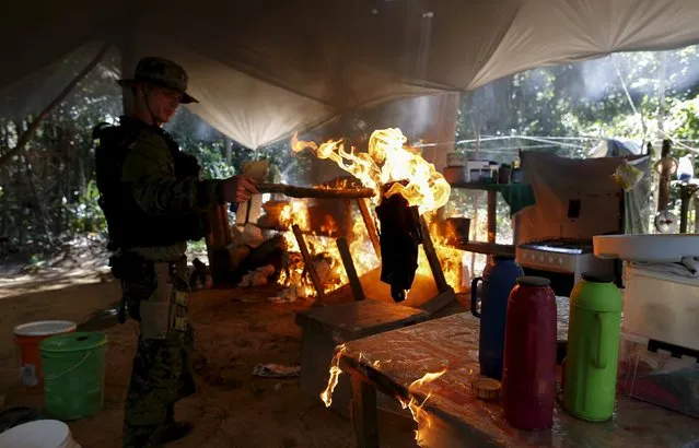 An agent of Brazil’s environmental agency burns a miners camp on the banks of Uraricoera River during an operation against illegal gold mining on indigenous land, in the heart of the Amazon rainforest, in Roraima state, Brazil April 15, 2016. (Photo by Bruno Kelly/Reuters)