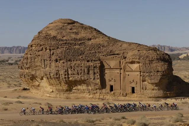 The peloton passes by ancient Nabataean carved tombs as it crosses the archaeological site of al-Hijr (Hegra), during the first stage of the Saudi Tour from Winter Park near Saudi Arabia's northwestern city of al-Ula on February 1, 2022. Dating back to the first century BC, the archaeological site, which is now open to tourists, includes 111 tombs most of which boast a decorated facade, cave drawings and even some pre-Nabataean inscriptions. (Photo by Thomas Samson/AFP Photo)