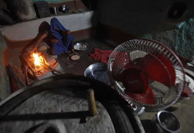 A woman cooks food in her kitchen illuminated by solar energy at Meerwada village of Guna district in Madhya Pradesh June 18, 2012. (Photo by Adnan Abidi/Reuters)s