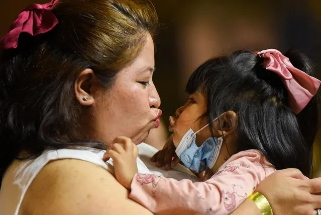 A woman kisses he child while waiting for the New Year countdown at Eastwood Mall, in Quezon City, Philippines, December 31, 2021. (Photo by Lisa Marie David/Reuters)