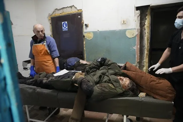 Morgue workers look at the body of a killed volunteer of Ukraine's Territorial Defense Forces at a hospital in Brovary, outside Kyiv, Ukraine, Tuesday, March 1, 2022. (Photo by Efrem Lukatsky/AP Photo)