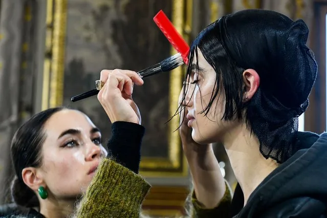 A model has her hair done ahead of Yohji Yamamoto Fall-Winter 2022/2023 Women's ready-to-wear collection show during Paris Fashion Week in Paris, France, March 4, 2022. (Photo by Piroschka van de Wouw/Reuters)