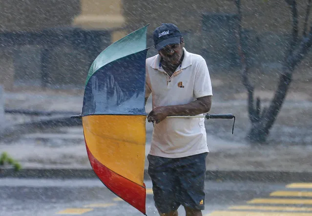 A man stuggles to hold his umbrella from high wind and rain during a wet day in Colombo , Sri Lanka May 15, 2016. (Photo by Dinuka Liyanawatte/Reuters)