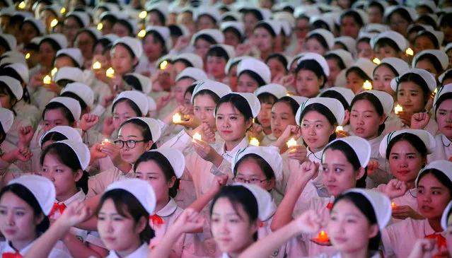 Nursing students holding candle shaped lights attend a ceremony ahead of the International Nurses Day on April 27, 2017 in Taiyuan, Shanxi Province of China. 670 nursing students of a health school received nurses' caps during a ceremony on Thursday in Taiyuan. (Photo by VCG/VCG via Getty Images)
