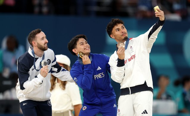 (L-R) Silver medalist Artem Dolgopyat of Team Israel, Gold medalist Carlos Edriel Yulo of Team Philippines and Bronze medalist Jake Jarman of Team Great Britain pose for a selfie on the podium during the medal ceremony for the Artistic Gymnastics Men's Floor Exercise Final on day eight of the Olympic Games Paris 2024 at Bercy Arena on August 03, 2024 in Paris, France. (Photo by Julian Finney/Getty Images)