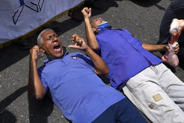 People lie down on a street as they scream demanding better salaries for workers, pensioners and retirees, during a protest in Caracas, Venezuela, Wednesday, April 6, 2022. (Photo by Ariana Cubillos/AP Photo)
