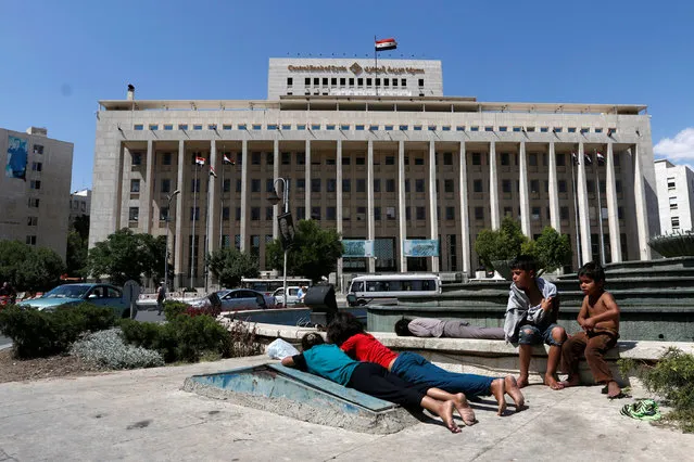 Homeless children rest on the sides of a fountain near the Central Bank of Syria in Damascus, Syria May 31, 2016. (Photo by Omar Sanadiki/Reuters)