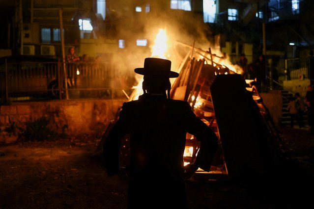 Ultra-Orthodox Jewish people watch a bonfire built in celebration of the Jewish holiday of Lag B'Omer in the Mea Shearim neighbourhood of Jerusalem on May 8, 2023. (Photo by Ronen Zvulun/Reuters)