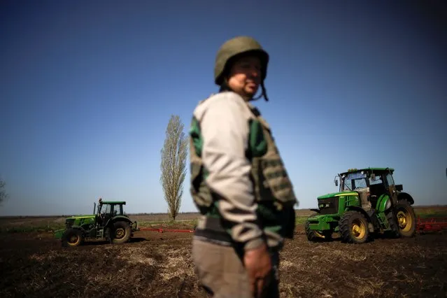 Oleksiy, a Ukrainian farmer, wearing body armour and helmet, works at the topsoil in a field, amid Russia's invasion of Ukraine, in Zaporizhzhia region, Ukraine on April 26, 2022. (Photo by Ueslei Marcelino/Reuters)
