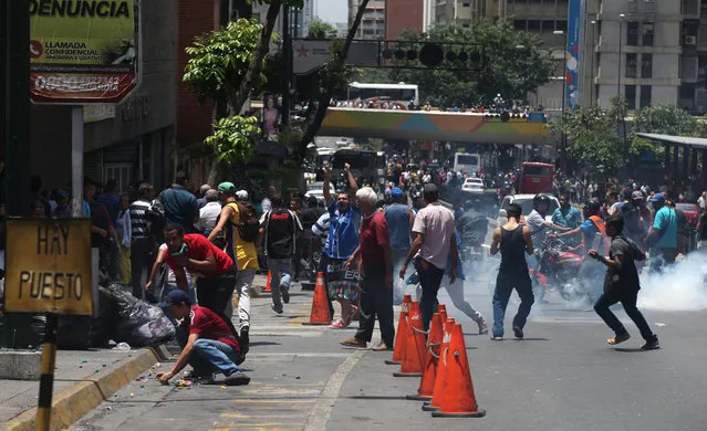 People scatter as Bolivarian National Police fire tear gas at their protest to demand food, a few blocks from Miraflores presidential palace in Caracas, Venezuela, Thursday, June 2, 2016. (Photo by Fernando Llano/AP Photo)