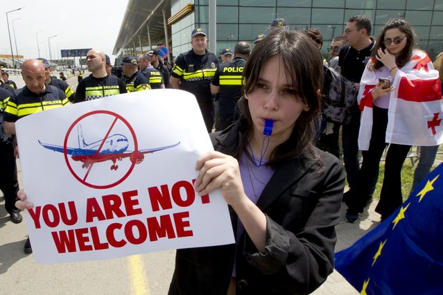 A Georgian opposition activist holds a placard during a protest against the resumption of air links with Russia, standing behind a police line at the International Airport outside Tbilisi, Georgia, Friday, May 19, 2023. Direct flights resumed on Friday between Russia and Georgia amid protests and sharp criticism from the South Caucasus nation's president, just over a week after the Kremlin unexpectedly lifted a four-year-old ban despite rocky relations. (Photo by Shakh Aivazov/AP Photo)