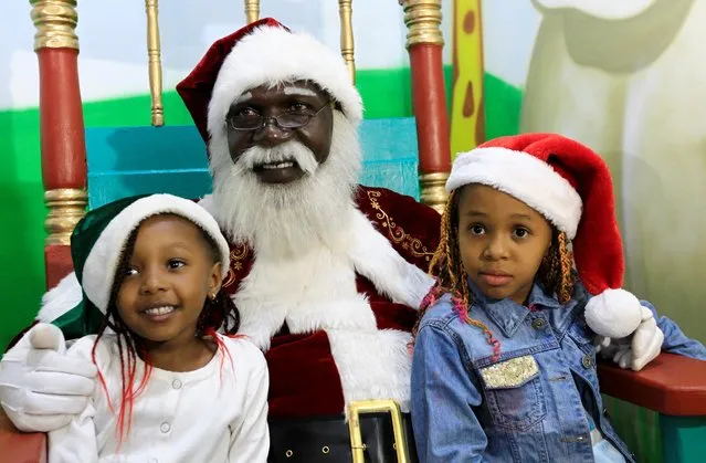 African Santa Claus Zedekiah Miyare, 56, poses for a photograph with children at a shopping mall ahead of Christmas in Nairobi, Kenya on December 21, 2019. (Photo by Njeri Mwangi/Reuters)