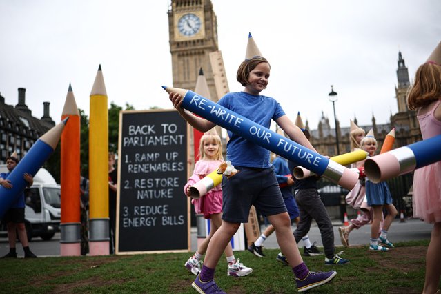 Children hold life-sized school kit props reading messages like “Re-Write our Future” or “Back to Parliament : Ramp up renewables, restore nature and reduce energy bills” as part of a “Back to School, Back to Parliament” rally organise by Mothers Rise Up outside of the Palace of Westminster, home to the Houses of Parliament, in central London, on September 2, 2024. Members of Parliament return to Westminster on September 2, 2024 after the summer break. (Photo by Henry Nicholls/AFP Photo)