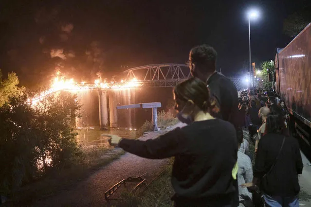 People look at flames engulfing the Industry Bridge in Rome, early Sunday, October 3, 2021. A blaze, possibly sparked by a gas canister explosion, destroyed part of an historic bridge spanning the Tiber River in Rome before firefighters extinguished the flames early Sunday. (Photo by Mauro Scrobogna/LaPresse via AP Photo)
