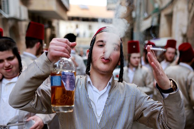 A person smokes as ultra-orthodox Jewish men gather as they mark the Jewish holiday of Purim, a celebration of the Jews' salvation from genocide in ancient Persia, in the Mea Shearim neighbourhood of Jerusalem, on March 25, 2024. (Photo by Ammar Awad/Reuters)