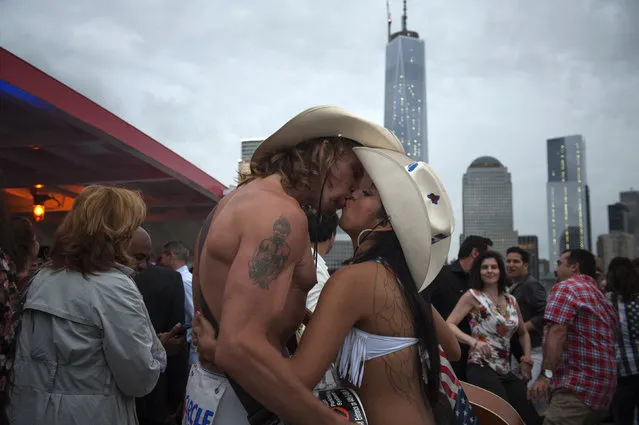 Robert Burck and his wife Patricia Cruz share a kiss between performances on a party boat which was cruising past Lower Manhattan in New York on June 6, 2013. Burck, better known as the original “Naked Cowboy”, started performing in Time Square in 1998. (Photo by Darren Ornitz/Reuters)