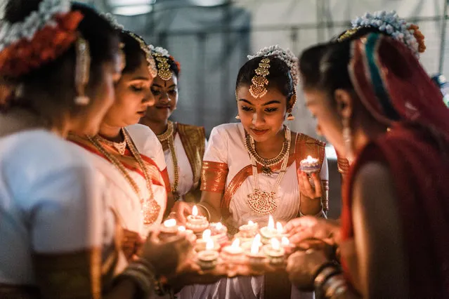 A group of colourful dancers from the Kumari Shiksha Dance Institution light colourful clay lamps in preparation to celebrate Diwali during the two day Diwali (Festival of Lights) Hindu festival celebrations at the old Drive-Inn in Durban, on October 19, 2019. The two-day festival attracts over 100,000 visitors. The festival celebrations include, parading of floats, chariots, singing of devotional songs, dances, games, face painting, food stalls of vegetarian food, clothing, display of toys and jewellery. Young people also get the opportunity to showcase their cultural and spiritual talents. A billion Hindus worlwide will officially celebrate Diwali on 27 October 2019. (Photo by Rajesh Jantilal/AFP Photo)