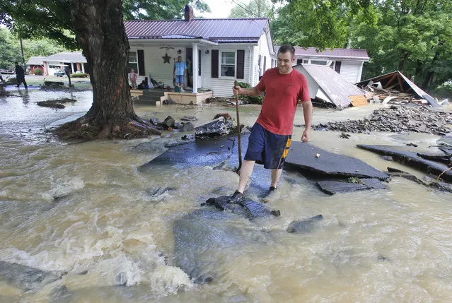 Mark Bowes, of White Sulphur Springs W. Va., makes his way to the road as he cleans up from severe flooding in White Sulphur Springs, W. Va., Friday, June 24, 2016. (Photo by Steve Helber/AP Photo)