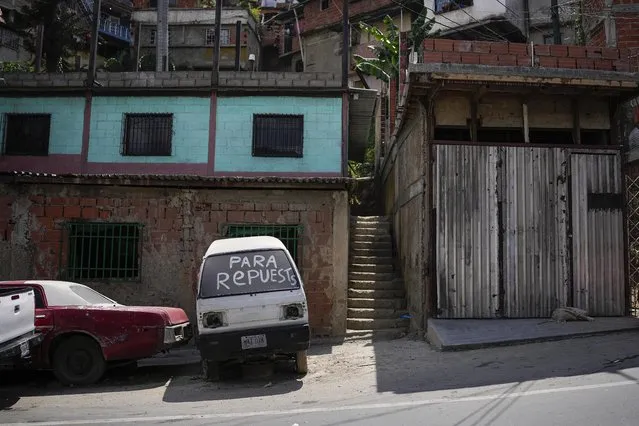 A derelict car with “For spare parts”, written in Spanish on its windshield sits parked in the San Juan neighborhood of Caracas, Venezuela, Tuesday, April 19, 2022. While used cars are banned for import, old cars make up the majority of the capital's vehicular fleet and are expensive to maintain. (Photo by Matias Delacroix/AP Photo)