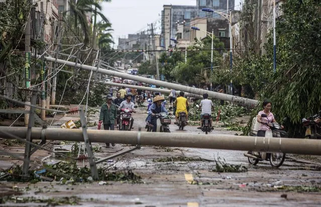 Residents travel on a street blocked by fallen electricity poles after Typhoon Rammasun hit Leizhou, Guangdong province July 19, 2014. A super typhoon has killed at least fourteen people in China since making landfall on Friday afternoon, state media said on Saturday, after hitting parts of the Philippines and leaving 77 dead. (Photo by Reuters/Stringer)
