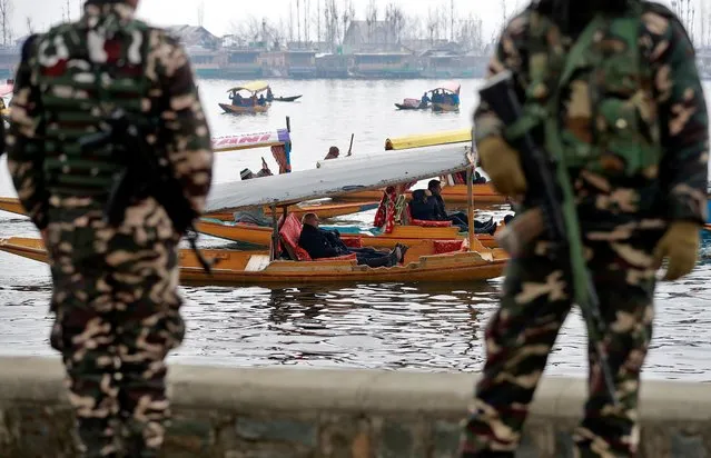 Foreign diplomats are seen in boats as Indian security force personnel stand guard on the banks of Dal Lake in Srinagar February 12, 2020. (Photo by Danish Ismail/Reuters)