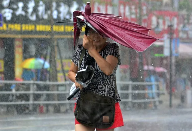 A woman holds her broken umbrella as she walks against strong wind and heavy rainfall as Typhoon Matmo hit Qingdao, Shandong province July 25, 2014. Matmo, which made landfall in Fujian Province on Wednesday, has brought strong winds and heavy downpours to more areas in China after it moved northward on Thursday, Xinhua News Agency reported. (Photo by Reuters/Stringer)