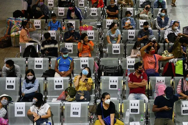 People wearing protective face masks, sit on social distancing benches at a bus station after many workers crowded the terminal station to return to their cities after many activities have been closed due to coronavirus disease (COVID-19) outbreak, Thailand on March 22, 2020. (Photo by Challinee Thirasupa/Reuters)
