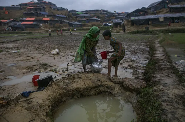 Women gather water from a hole that the surrounding households use for washing, drinking, cooking and bathing in the Balukhali camp on September 18, 2017 in Cox's Bazar, Bangladesh. Nearly 400,000 Rohingya refugees have fled into Bangladesh since late August during the outbreak of violence in the Rakhine state as recent satellite images released by Amnesty International provided evidence that security forces were trying to push the minority Muslim group out of the country. Myanmar's de facto leader Aung San Suu Kyi cancelled her trip to the United Nations General Assembly in New York, which begins next week, while criticism on her handling of the Rohingya crisis grows and her government has been accused of ethnic cleansing. According to reports, the Rohingya crisis has left at least 1,000 people dead, including children and infants, with dozens of the Rohingya Muslims who drowned when their boat capsized while trying to escape on overloaded fishing boats ill-equipped for rough waters. (Photo by Allison Joyce/Getty Images)