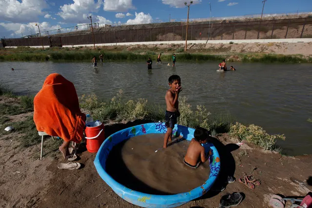 Children play in an inflatable pool to cool off during a hot summer day on the Mexican side of the Rio Bravo near the fence marking the border between Mexico and the U.S in Ciudad Juarez, Mexico, July 24, 2016. (Photo by Jose Luis Gonzalez/Reuters)