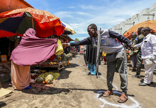 A Somali woman sells fruits to a customer standing at a social distancing signage, as a measure to stem the growing spread of the coronavirus disease (COVID-19) outbreak, at the market centre in Hamarweyne district in Mogadishu, Somalia on April 16, 2020. (Photo by Feisal Omar/Reuters)