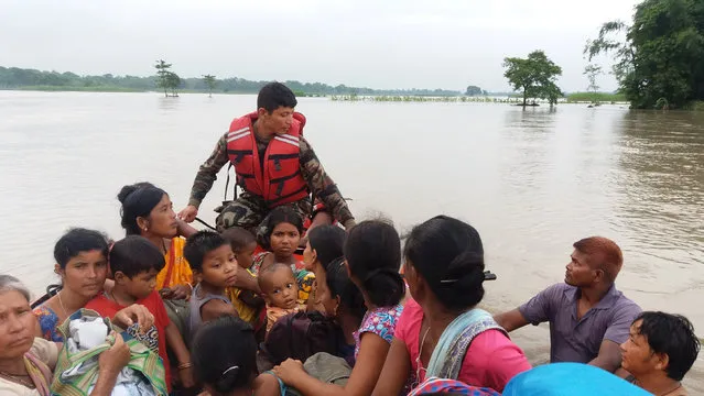 An army officer assists flood victims in Jhapa, Nepal, July 24, 2016. (Photo by Reuters/Nepalese Army)