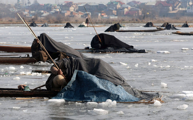 Kashmiri fishermen cover their heads and part of their boats with blanket and straw as they catch fish on the frozen waters of the Anchar Lake in Srinagar, the summer capital of Indian Kashmir, 08 January 2025. In winter months every year from 21 December to 30 April the Kashmiri fishermen use unique method of camouflaging their presence to lure the fish into a trap with the help of reeds and shock waves by beating the water. (Photo by Farooq Khan/EPA/EFE)