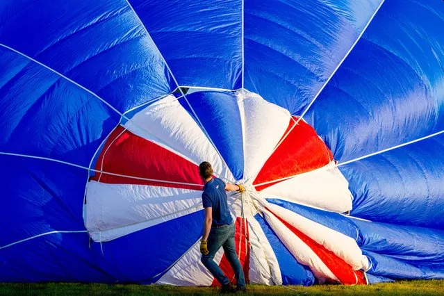 Hot air balloons are inflated prior to taking off at Ashton Court during the Bristol International Balloon Fiesta in southwest England on August 11, 2022. The Fiesta runs for four days until August 12. (Photo by Marcin Nowak/London News Pictures)