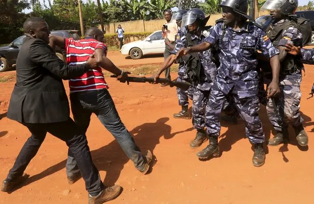 A supporter of Uganda's former Prime Minister Amama Mbabazi wrestles with the gun of a policeman, as riot police disperse a gathering in Jinja town in eastern Uganda September 10, 2015. (Photo by James Akena/Reuters)