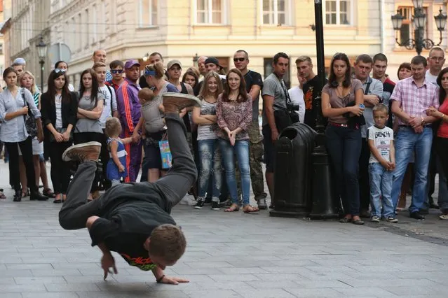 People watch a break dancer peform on a Sunday afternoon in the city center on Rynok Square on September 14, 2014 in Lviv, Ukraine. Hundreds of miles away sporadic fighting between pro-Russian separatists and the Ukrainian army in eastern Ukraine is continuing and many people doubt the current ceasefire overtures will lead to an end to the war. (Photo by Sean Gallup/Getty Images)