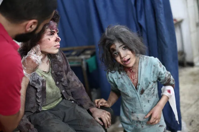 A Syrian medical worker treats a young girl, as another looks on, at a makeshift hospital in the rebel-held town of Douma near Damascus on September 14, 2014, after reported airstrikes by Syrian government forces. Douma is a rebel bastion northeast of Damascus, which has been under suffocating army siege for more than a year. Syria's war has killed more than 170,000 people, and forced nearly half the population to flee their homes. (Photo by Abd Doumany/AFP Photo)