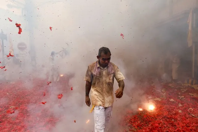 A man walks amidst bursting firecrackers as people participate in a procession during the annual vegetarian festival, observed by Taoist devotees from the Thai-Chinese community in the ninth lunar month of the Chinese calendar, in Takua Pa in the Phang Nga province, Thailand on October 1, 2022. (Photo by Jorge Silva/Reuters)