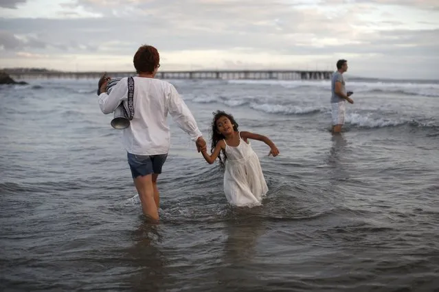 Gena Lindenbaum, 50, (L) dances in the ocean with Audrey Klein, 5, during the Nashuva Spiritual Community Jewish New Year celebration on Venice Beach in Los Angeles, California, United States September 14, 2015. (Photo by Lucy Nicholson/Reuters)