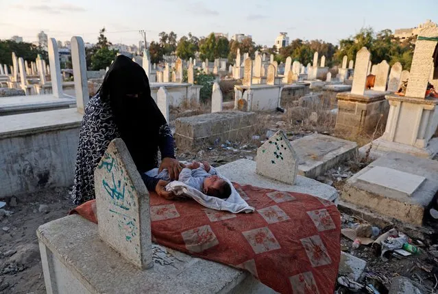 Kamilia Kuhail, 35, looks after her 2 month old son, Ahmed, in the Sheikh Shaban cemetery where she lives with her family, in Gaza City, August 27, 2022. The Kuhail family's house was built on the graves of two unknown people whose remains are now buried under the foundations. “If the dead could talk, they would tell us, get out of here”, said Kamilia who has lived in the cemetery for 13 years with her husband and a family now numbering six children. (Photo by Mohammed Salem/Reuters)