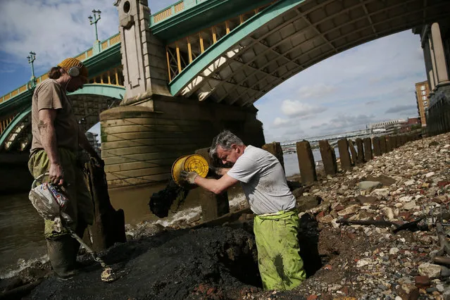 Mudlarks Andy Johansen and Ian Smith dig holes as they look for objects under Southwark Bridge on the bank of the River Thames in London, Britain May 22, 2016. (Photo by Neil Hall/Reuters)