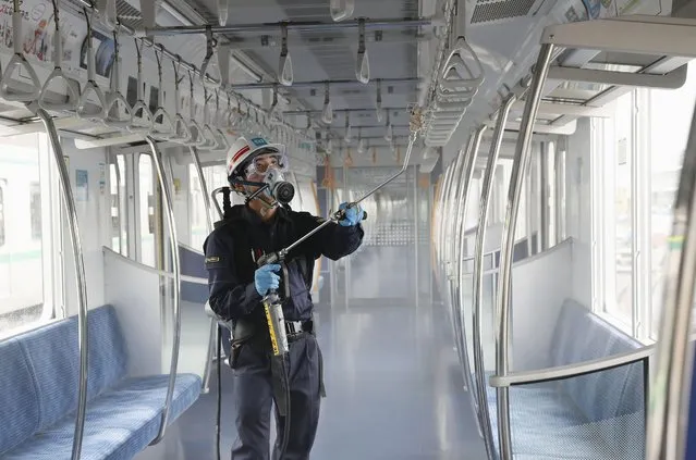 A Tokyo Metro worker, wearing goggle and protective mask, sprays chemicals to make anti-virus coating inside a passenger car at its depot Thursday, July 9, 2020, in Tokyo. The subway company plans to disinfect all 2720 cars by mid August this year, Kyodo News reported.  Japan lifted a seven-week pandemic state emergency in late May, and social and business activity have since largely resumed. (Photo by Kyodo News via AP Photo)