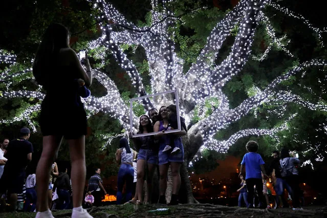 A woman takes a picture of a family near trees decorated with Christmas lights at Ibirapuera Park in Sao Paulo, Brazil December 3, 2017. (Photo by Nacho Doce/Reuters)