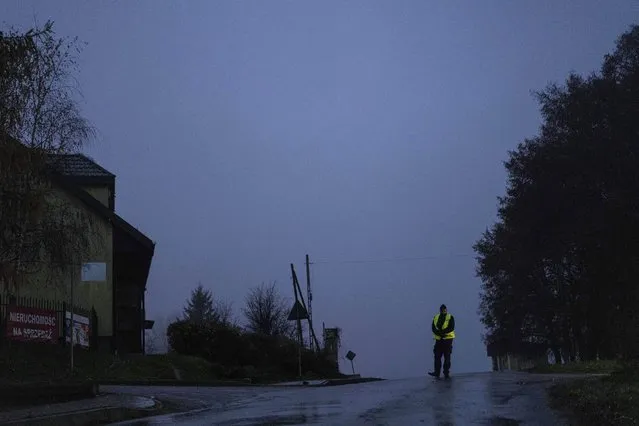 A police officer stands at a checkpoint near the scene of a blast in Przewodow, Poland, Wednesday, November 16, 2022. Poland said Wednesday that a Russian-made missile fell in the country’s east, though U.S. President Joe Biden said it was “unlikely” it was fired from Russia. (Photo by Evgeniy Maloletka/AP Photo)