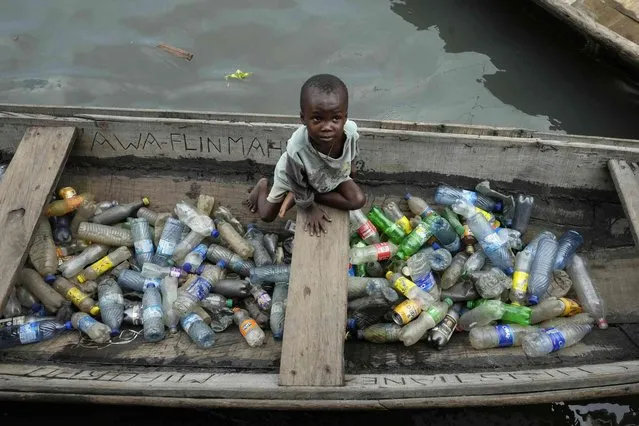 A child sits inside a canoe with empty plastic bottles he collected to sell for recycling in the floating slum of Makoko in Lagos, Nigeria, Tuesday, November 8, 2022. The COP27 U.N. Climate Summit is taking place in Sharm el-Sheikh, Egypt. (Photo by Sunday Alamba/AP Photo)