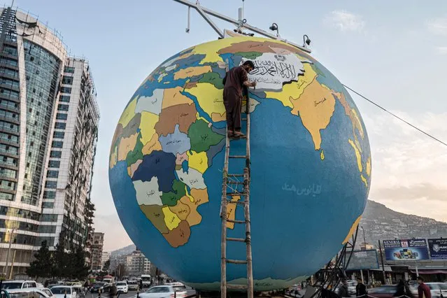 In this photograph taken on December 6, 2022, a painter gives final touches to a large hand-painted globe of planet Earth installed by municipal authorities at the Dahan-e Bagh square in Kabul. Afghanistan's capital has a bold new landmark that puts it at the centre of the world – or rather the world at the centre of Kabul. (Photo by Wakil Kohsar/AFP Photo)