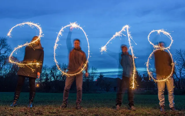 Illustration taken with a long time exposure on December 27, 2017 in Sieversdorf, eastern Germany, shows four people drawing the year “2018” with sparklers. (Photo by Patrick Pleul/AFP Photo/DPA)