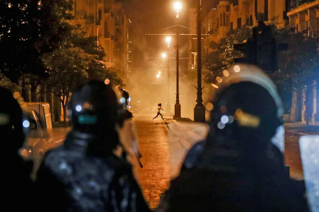 A Lebanese protester runs to avoid tear gas amid clashes with security forces in downtown Beirut on August 11, 2020, following a huge chemical explosion that devastated large parts of the capital. (Photo by Joseph Eid/AFP Photo)