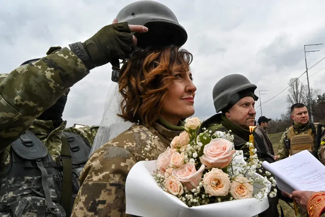 Servicemen of Ukrainian territorial defence, Valery (2ndR) and Lesya (L), get married not far from check-point on Kyiv outskirts on March 6, 2022. (Photo by Genya Savilov/AFP Photo)
