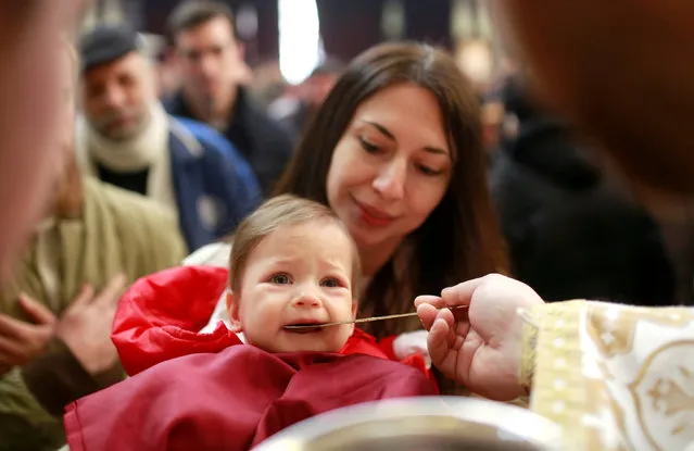 A baby receives the sacraments during the Orthodox Christmas mass at the St. Clement Cathedral in Skopje, Macedonia, January 7, 2018. (Photo by Ognen Teofilovski/Reuters)