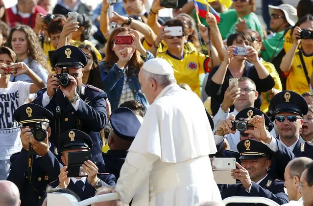 Italian policemen take pictures as Pope Francis arrives to lead the weekly audience in Saint Peter's Square at the Vatican October 7, 2015. (Photo by Tony Gentile/Reuters)